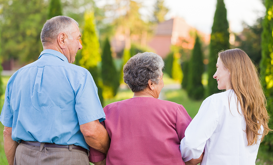 Elderly couple walking in the nature with the carer