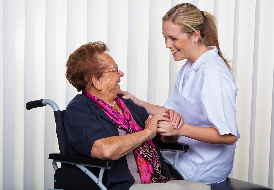 a caregiver and an elderly woman in a wheelchair.